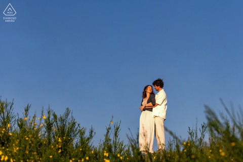 A couple standing for a portrait in the countryside near Autun, surrounded by rolling hills and vibrant greenery.