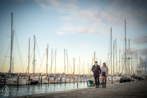 A couple walks romantically between sailboats at Venice's marina, surrounded by a serene maritime setting.