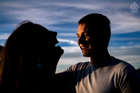 A couple in Utrecht laughs together, playfully interacting with the warm, golden sunset light, creating a joyful atmosphere.