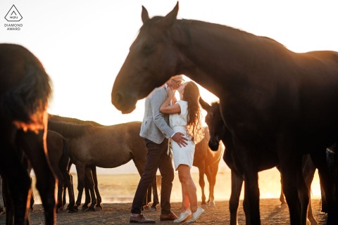 Couple kisses surrounded by horses during Cappadocia pre-wedding photo session in Kayseri, Turkey.