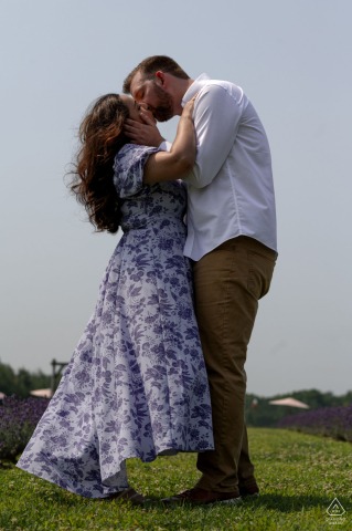Engaged couple embracing and kissing in lush lavender fields at Maison Lavande, Sainte-Eustache, Quebec, vertical portrait shot.