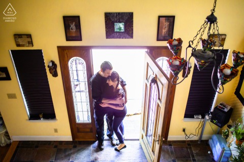 Engaged couple embracing inside doorway, viewed from above in San Jose, California, creating an intimate and cozy indoor portrait.
