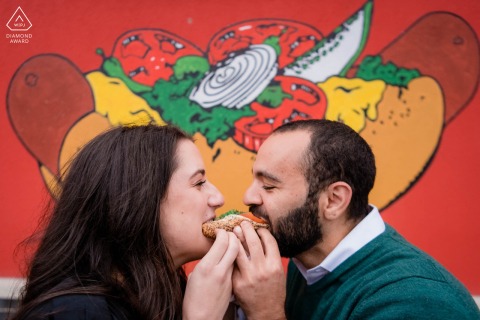 Couple shares a hotdog outside Victory Grill in Chicago’s Logan Square during their engagement session.