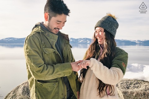 Engaged couple in snowy South Lake Tahoe, smiling as bride-to-be joyfully shows off engagement ring.