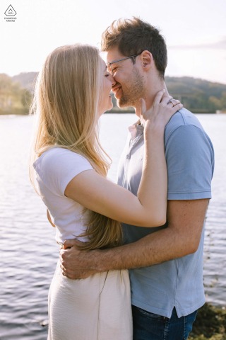 Romantic Sunset Embrace: Couple Kisses at Biggesee Lake, Sauerland, Germany Waterfront Glow Couple kissing and embracing at Biggesee lake, sunset glow reflecting on water, Sauerland, Germany.