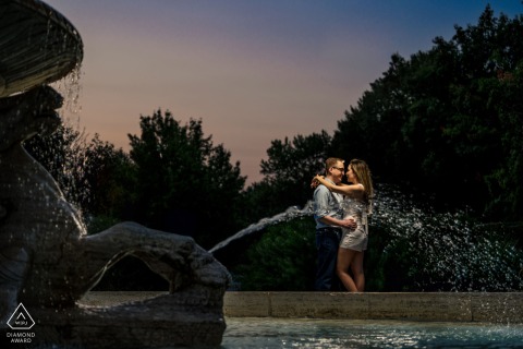 Engaged couple nearly kissing in Philadelphia, vibrant fountain in background mirroring their romantic chemistry.