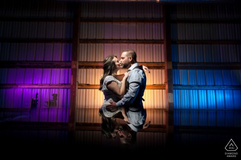 A couple kisses center frame in Philadelphia, surrounded by vibrant, colorful lights on both sides.