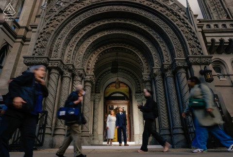 Engaged couple stands in loving stillness at Philadelphia City Hall, surrounded by timeless architecture and footsteps.