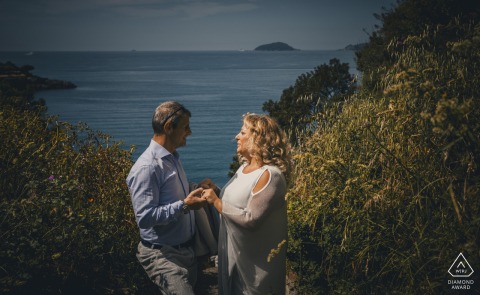 Engaged couple in Lerici, by the sea, holding hands and sharing loving eye contact.