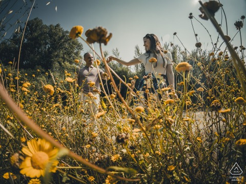 Engaged couple in Ceparana, dancing joyfully together amidst a vibrant field of yellow flowers.