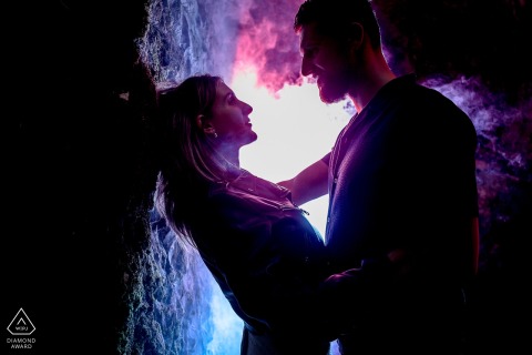 A couple poses in Sassenage, France, illuminated by romantic lights and dreamy swirling smoke.