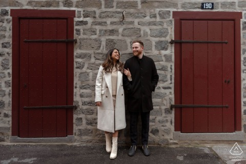 Happy couple with big smiles stand together after proposal, against historic Old Montreal building facade.