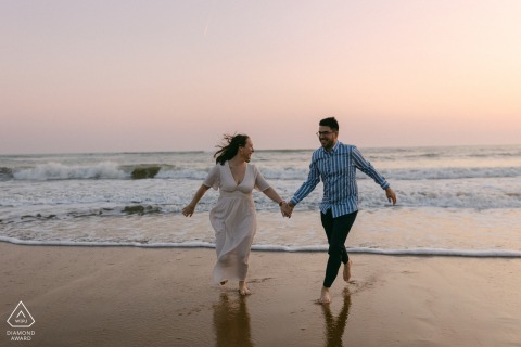 Engaged couple in ocean at Les Sables d’Olonne, backlit by vibrant, romantic sunset glow.