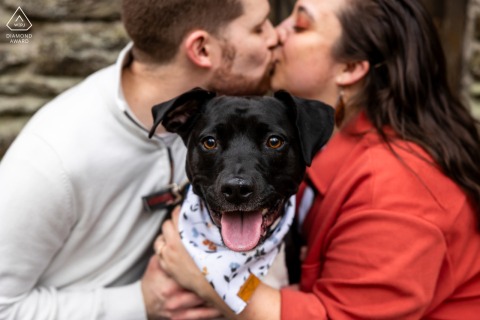 A couple kisses in Wissahickon Park, Philadelphia, while their dog adorably stares at camera.