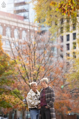 A couple gazes at each other behind a historic bank on Independence Mall, surrounded by colorful fall foliage.