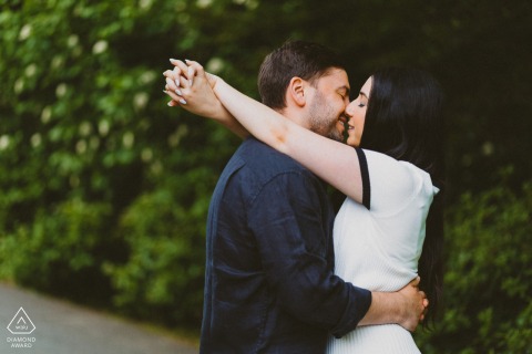 Engaged Couple Shares a Kiss Embraced in Brookside Gardens’ Lush Greenery, Tender Portrait Couple embraces and shares a kiss in Brookside Gardens, surrounded by lush greenery.