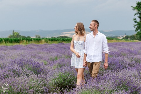 A couple walks hand in hand through blooming purple lavender fields near Clermont-Ferrand, looking serene.