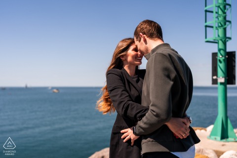 Engaged couple hugging in windy Portopiccolo, Sistiana, Trieste, Italy, with sea and hills.
