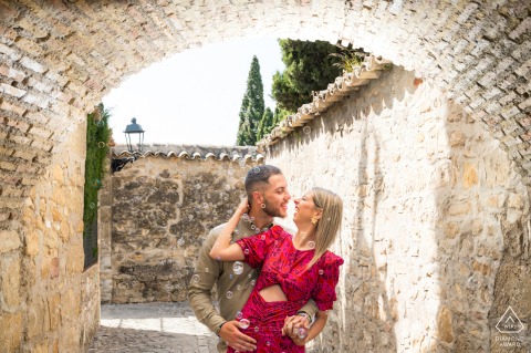 Romantic pre-wedding couple, deeply engrossed, surrounded by brick architecture, Baeza, Jaén, Spain, portrait.