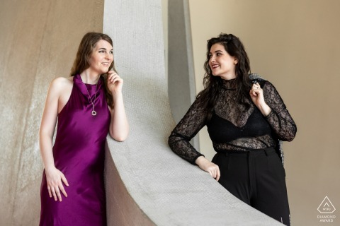 Couple stands on opposite sides of dividing wall, gazing at each other, inside TWA Hotel.