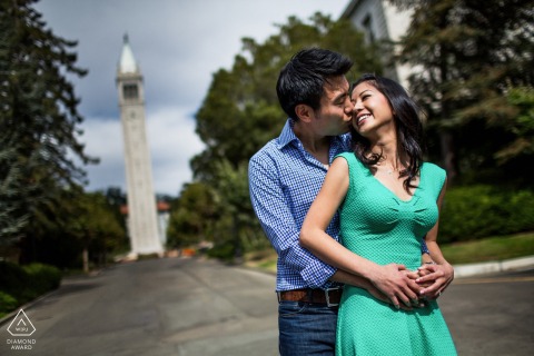 UC Berkeley, CA — Couple embraces on campus grounds with university tower in background.