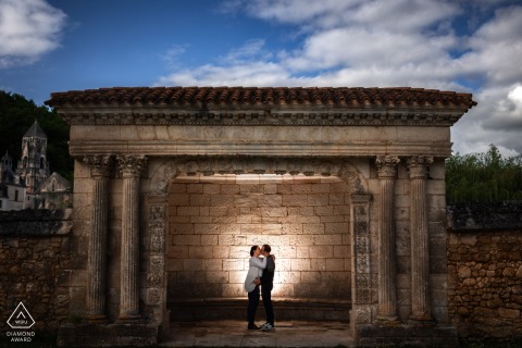 Engaged Couple Poses Before Historic Brantôme Monument In Picturesque Périgord, France Setting Brantôme, Périgord, France. An engaged couple poses in front of a historic monument.