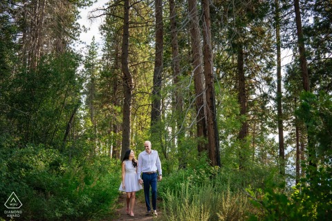 Couple embracing after a South Lake Tahoe proposal in a forest of tall trees.