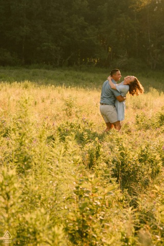 AUGUSTA, Maine — A couple enjoys a whimsical, sun-drenched summer engagement session, surrounded by a vibrant field of yellow foliage, capturing their romantic connection.