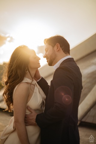 BRASILIA, Brazil — A couple shares a romantic embrace, their faces close as the sun sets behind them. This warm, vertical portrait captures their deep connection.
