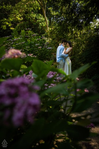 LYON, France — A couple is embraced by vibrant hydrangea blooms in a serene Parc des hauteurs engagement portrait. The flowers seem to protect and surround the happy pair.