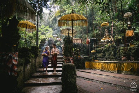 BALI — A couple descends the stairs at Taman Beji Griya Waterfall for a pre-wedding purification ritual. Their serene engagement portrait reflects a deeply spiritual and tranquil connection.