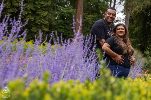 Engaged couple in Wardown Park, Luton, UK: surrounded by vibrant summer flowers, enjoying the colorful and romantic outdoors.