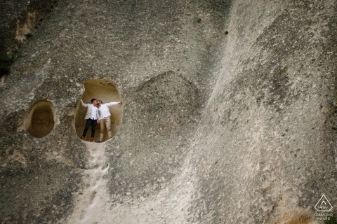 Engaged couple kisses at cave entrance in Goreme, Cappadocia, Turkey, surrounded by unique rock formations during pre-wedding session.