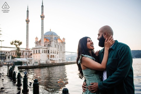 A couple embraces lovingly by the water near Ortakoy Mosque in Istanbul during their romantic pre-wedding photo session.
