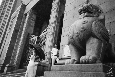A couple stands romantically by a grand doorway with stone lions on The Bund, Shanghai.