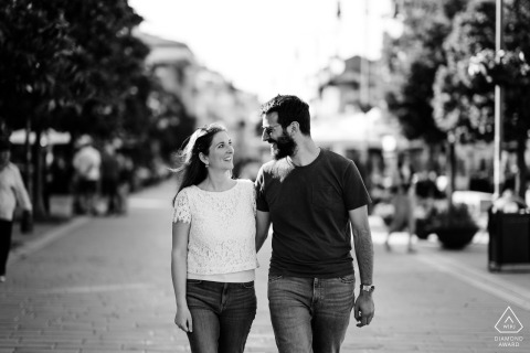 Grado, Gorizia, Italy — A couple walks together, gazing at each other in the middle of the street, captured in a classic black-and-white engagement portrait.