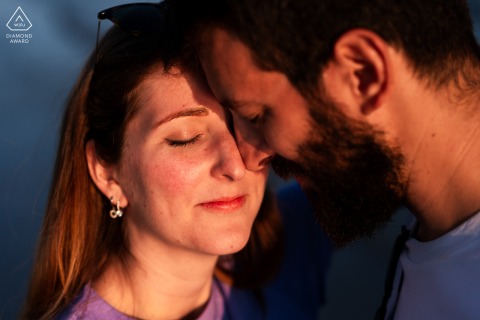 Grado, Gorizia, Italy — A couple touches faces in a close-up portrait at sunset, bathed in warm light, capturing intimacy and romance by the sea.
