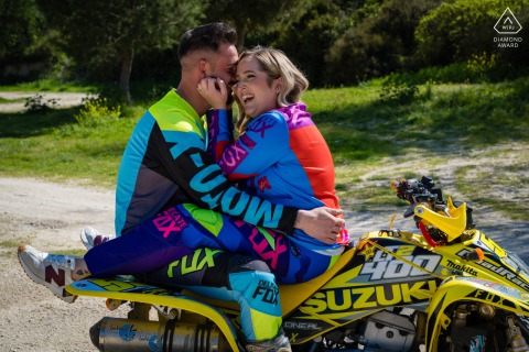 Santa Ana, Torredelcampo, Jaén, Spain — A couple sits facing each other, legs locked, on a yellow Suzuki quad in riding gear, capturing adventurous spirit in this pre-wedding portrait.