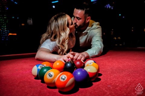 Café Central, Baeza, Jaén, Spain — A couple leans on a red felt pool table with billiard balls in the foreground, adding playful style to this pre-wedding portrait.