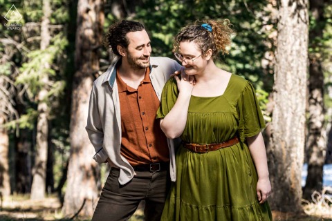 Golden, Colorado — A couple laughs together while walking closely in a sunlit park, capturing genuine joy and connection in this bright and heartfelt engagement portrait. 