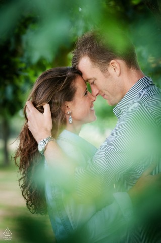 A romantic close-up portrait of a couple nestled beneath the branches of a tree at Chicheley Hall, their expressions warm and affectionate, with soft natural light filtering through the leaves.