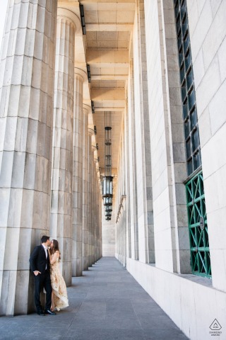 The lovers stand together for their engagement portrait at Buenos Aires Law School. The vertical shot features the couple framed by massive old-world stone pillars, emphasizing the building’s grand architectural backdrop.