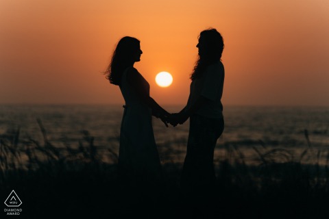 A couple standing by the ocean, profiles showing as a silhouette, embracing the fading sunset at Labruge beach.
