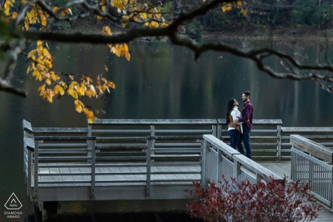 Happy Couple Embraces On Pier At Vogel State Park For Engagement Portrait A happy couple stands on a pier at Vogel State Park, embracing in their engagement portrait.