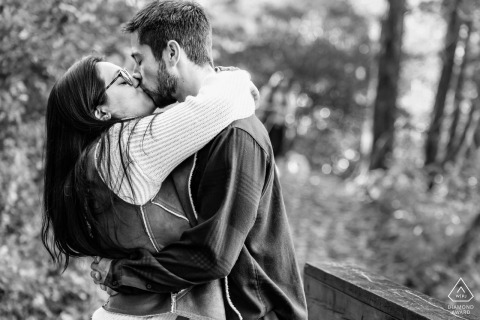 Kiss Under The Trees: A Black and White Engagement at Vogel State Park At Vogel State Park, a couple shares a passionate kiss in a black and white portrait, surrounded by towering trees that enhance the romantic atmosphere of their engagement session.