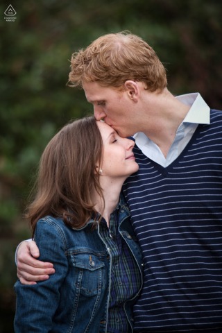 Newly Engaged Couple Shares Tender Moment On Mount Royal Chalet Balcony Edge Close-up engagement portrait in a Decatur backyard, with a loving kiss on the forehead.