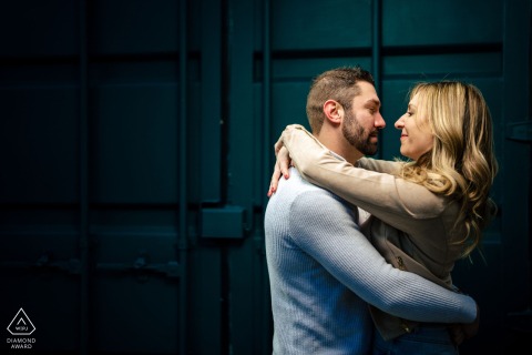 In LOVE Park, Philadelphia, a couple stands wrapped up in each other, expertly lit by the photographer. The urban setting and soft lighting create an intimate, romantic atmosphere for their engagement portrait.