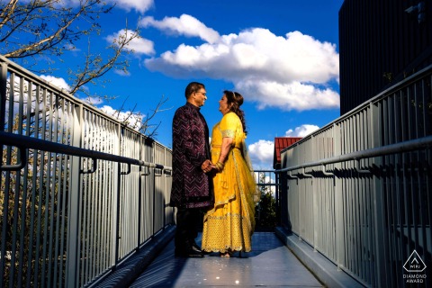 Joyful Couple Shines In Vibrant Traditional Attire, Philadelphia Love In Philadelphia, a couple stands together beneath a vast blue sky filled with big white clouds. Their vibrant traditional attire and joyful expressions reflect the brightness and richness of their shared culture.