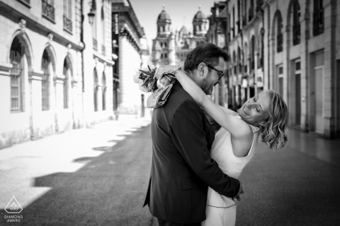 On Rue de la Liberté in Dijon, a couple embraces in a black and white urban portrait. Facing each other, she leans back as he holds her, surrounded by the city street.
