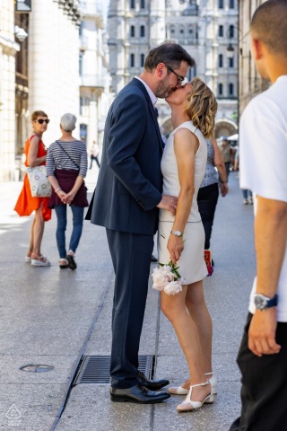 In Dijon, a couple stands together in an urban setting as pedestrians move around them on the bustling streets. Their connection stands out amid the lively city atmosphere in this engagement portrait.